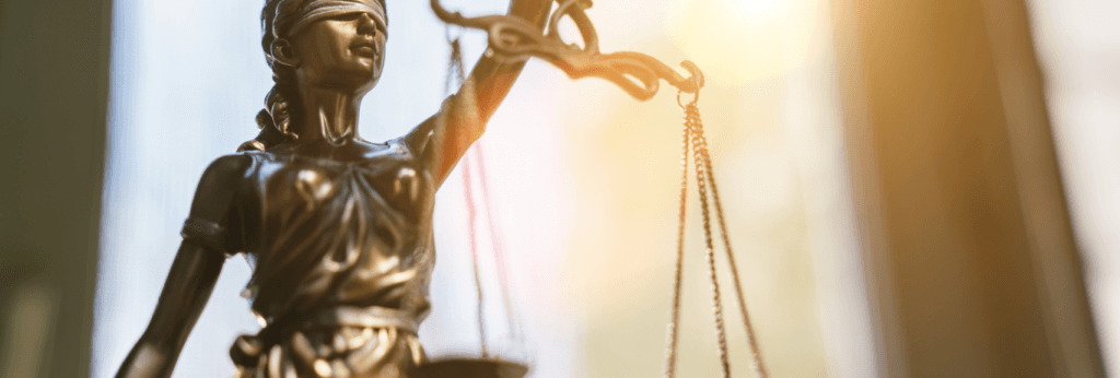A golden figurine of 'Lady Justice', a blindfolded woman holding a set of scales who represents a moral force in judicial systems.
